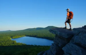 Hiking Giuffrida Park: Trails, Peaks & Essential Tips A hiker stands on the rocky summit of Chauncey Peak, looking at the panoramic view of Crescent Lake and Lamentation Mountain in Doctor Francis Giuffrida Park, Meriden, CT.