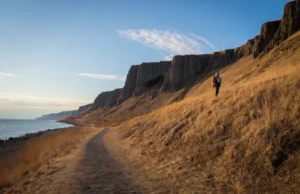 Palisade Park Trail: Beginner to Expert Guide A wide, scenic view of a hiking trail in Palisades Interstate Park at sunset, showing the path along the Hudson River and up the cliffs.