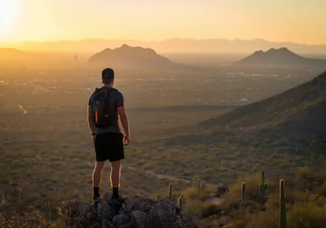 A dedicated hiker overlooks the best hiking places in Phoenix, with Camelback Mountain visible at sunset.