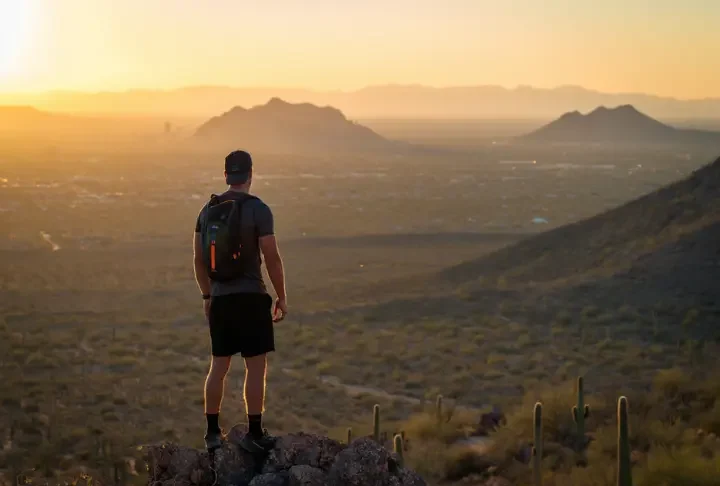 A dedicated hiker overlooks the best hiking places in Phoenix, with Camelback Mountain visible at sunset.
