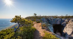 Sam’s Point Ice Cave: Hike, Falls & Views Guide A panoramic view of the Sam's Point Ice Cave trail leading to a dramatic overlook with the Shawangunk Mountains and Hudson Valley in the background.