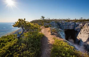 Sam’s Point Ice Cave: Hike, Falls & Views Guide A panoramic view of the Sam's Point Ice Cave trail leading to a dramatic overlook with the Shawangunk Mountains and Hudson Valley in the background.