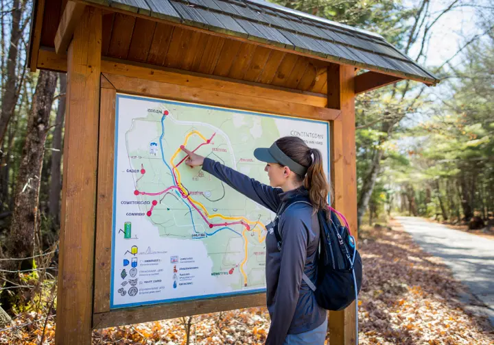 A hiker studies a trail guide map at a kiosk before starting a hike in a Connecticut state park.