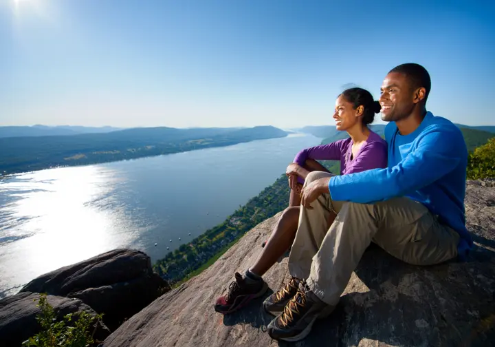 Two hikers enjoy the panoramic view of the Hudson River from the rocky summit of Storm King Mountain in Cornwall, NY.