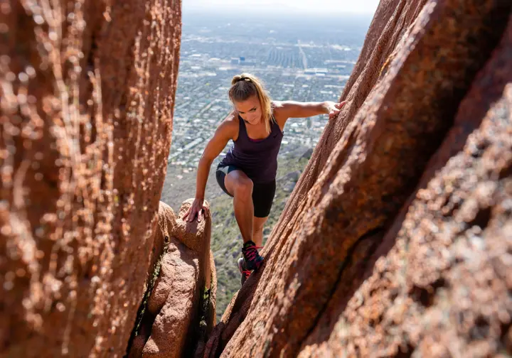 A female hiker scrambling on the iconic and difficult Echo Canyon Trail on Camelback Mountain in Phoenix.