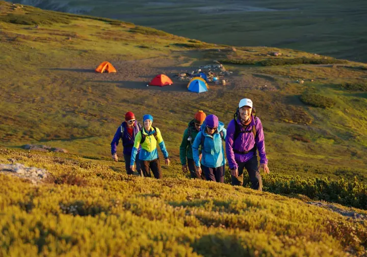 A group of hikers on an acclimatization day hike high above their campsite, demonstrating the "climb high, sleep low" prevention strategy for altitude sickness.