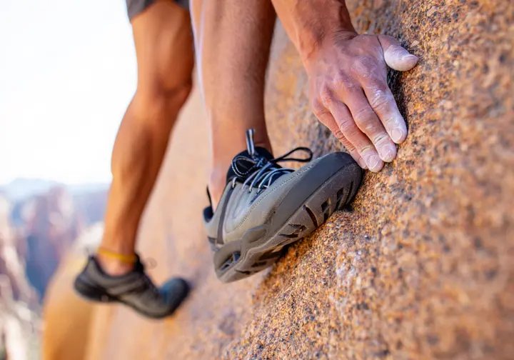Close-up of a hiker's specialized shoes and hands while scrambling, demonstrating advanced skills for Phoenix trails.