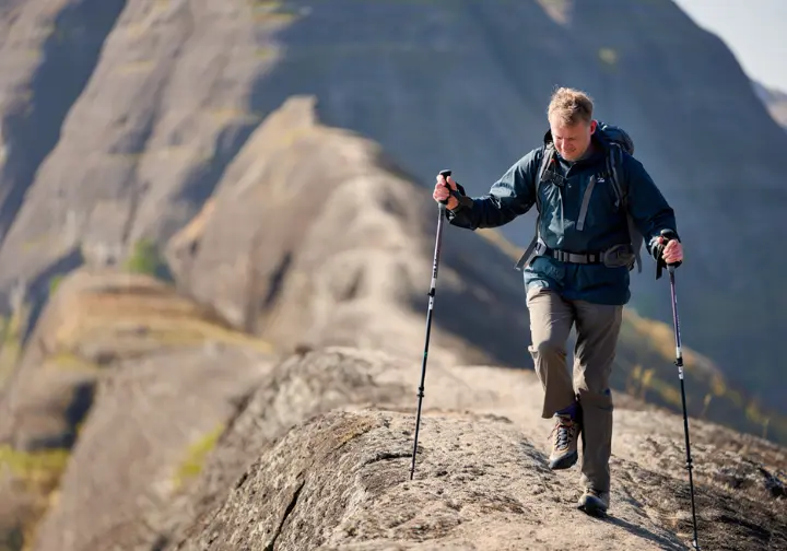 A responsible hiker using trekking poles for safety and stability while navigating the steep, rocky cliffs of a trail in Giuffrida Park.