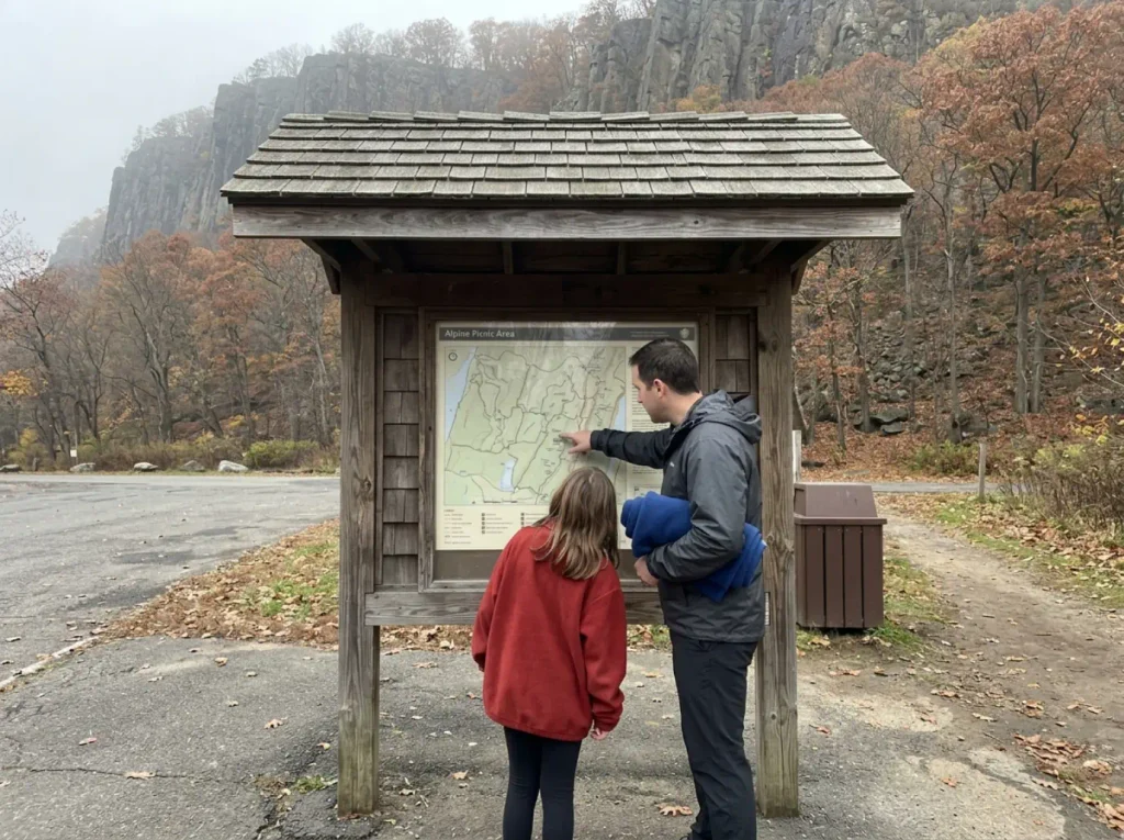 Family reading the trailhead map board at Alpine Picnic Area in Palisades Interstate Park