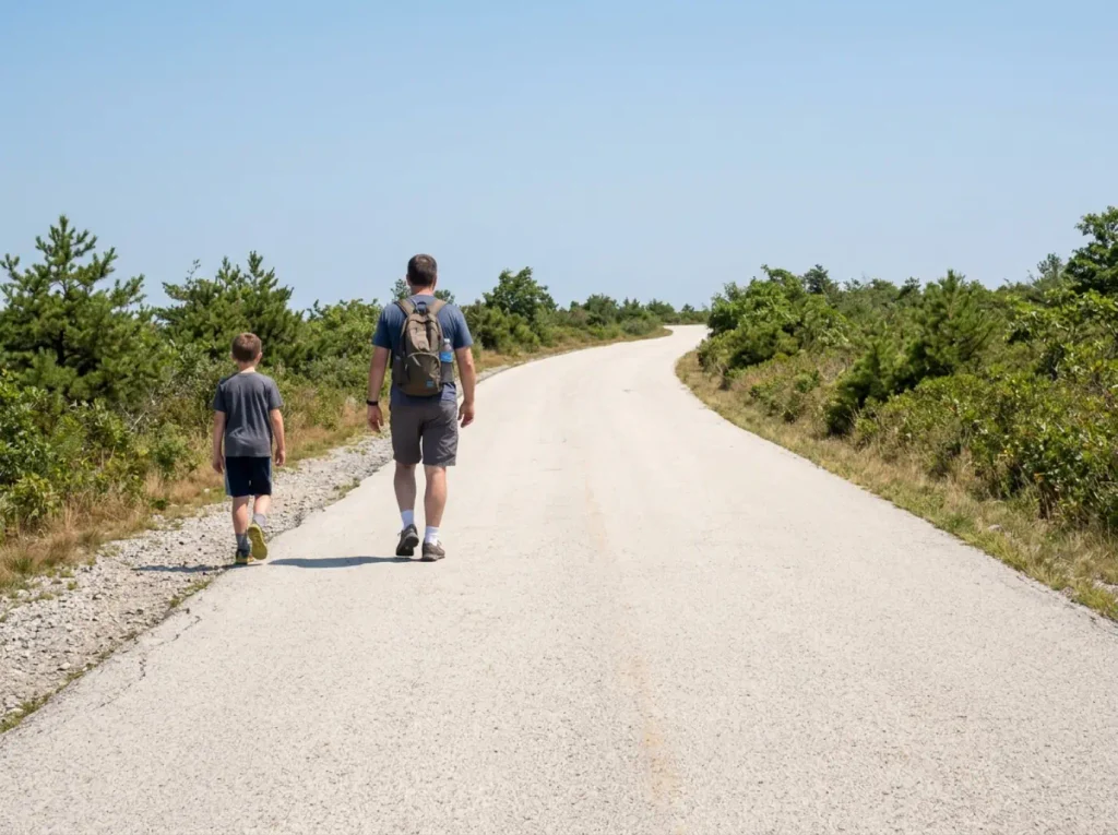 Two hikers walking the exposed uphill approach road to the Sam's Point Ice Cave through dwarf pine barrens