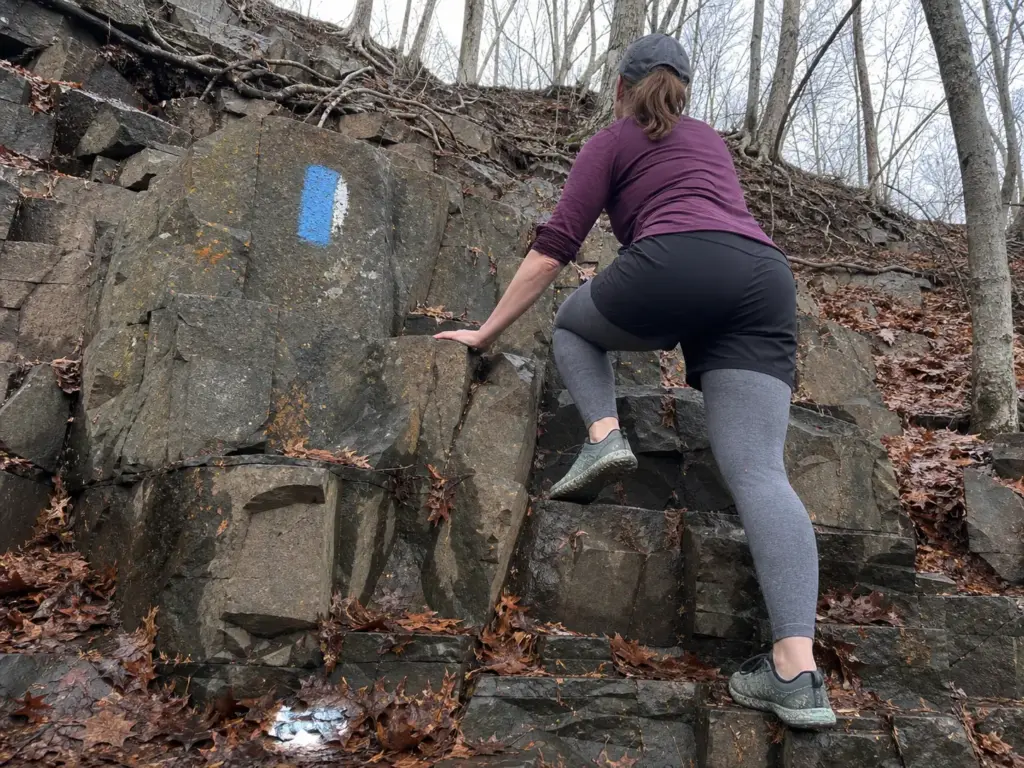 Hiker climbing the steep blue-blazed traprock section of the Chauncey Peak loop