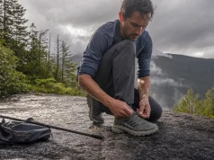 Why Hiking Shoe Technology Labels Tell You Almost Nothing Hiker retying a low-cut hiking shoe on wet granite, showing hiking shoe technology in real use