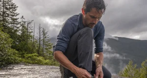 Why Hiking Shoe Technology Labels Tell You Almost Nothing Hiker retying a low-cut hiking shoe on wet granite, showing hiking shoe technology in real use