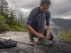 Why Hiking Shoe Technology Labels Tell You Almost Nothing Hiker retying a low-cut hiking shoe on wet granite, showing hiking shoe technology in real use