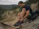 Trail Runners for Hiking Buying Guide for 2026 Hiker sitting on a rock retying trail runners mid-hike, hiking boots not needed