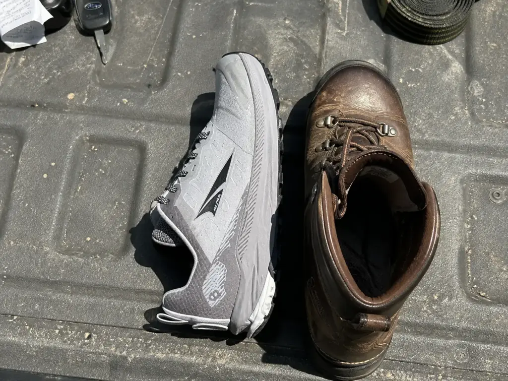 Trail runner and hiking boot side by side on a tailgate showing height and weight difference