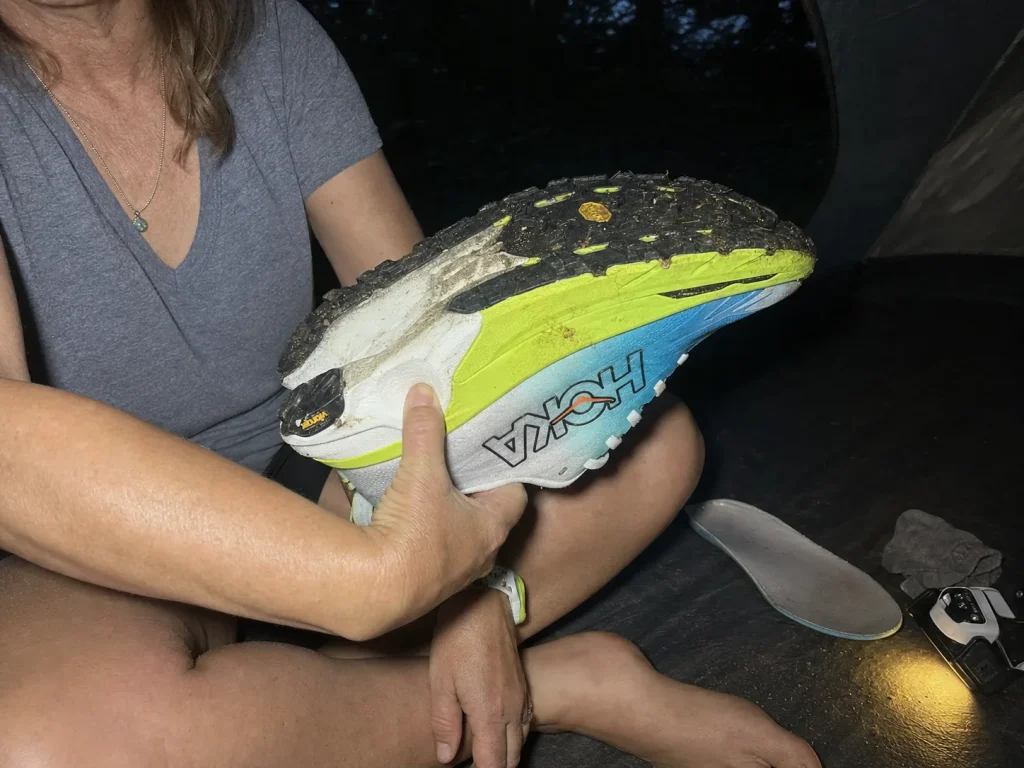 Thumb pressing into a hiking shoe midsole with the insole removed, testing for packed-out foam