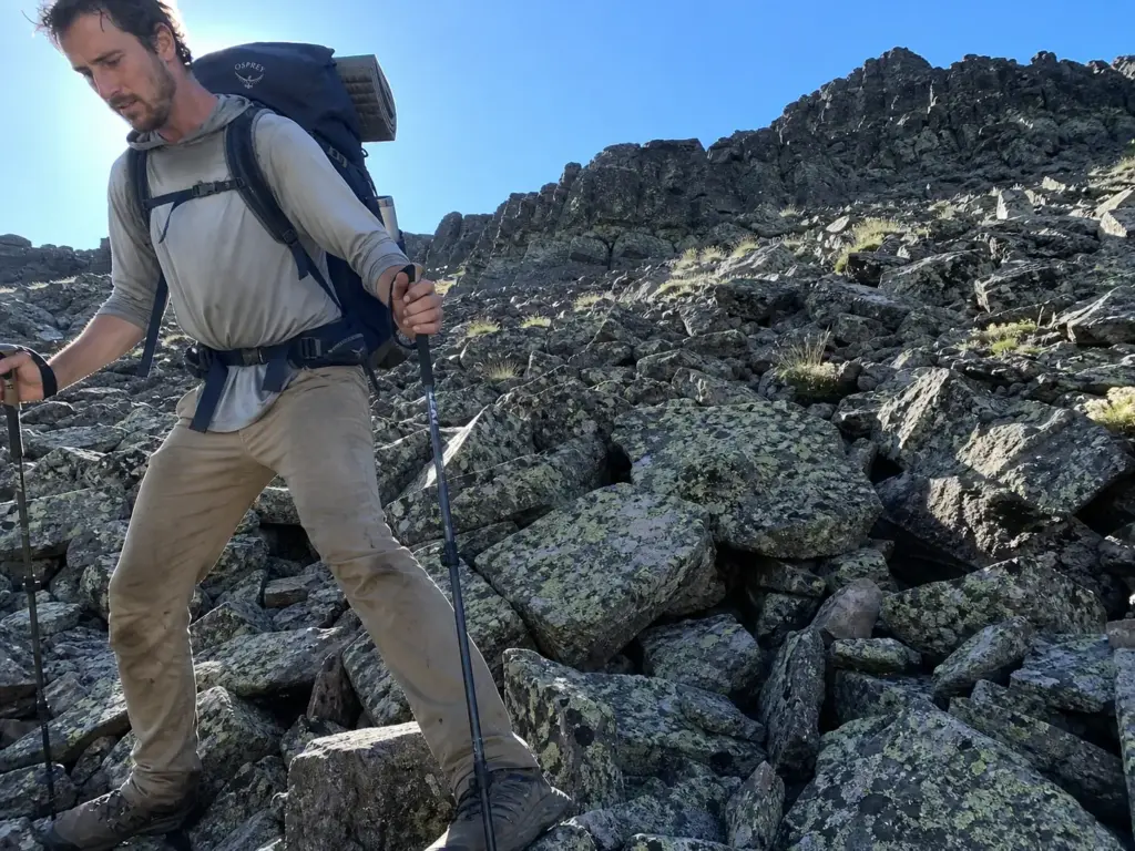 Backpacker with a heavy loaded pack picking a line across loose talus in low shoes