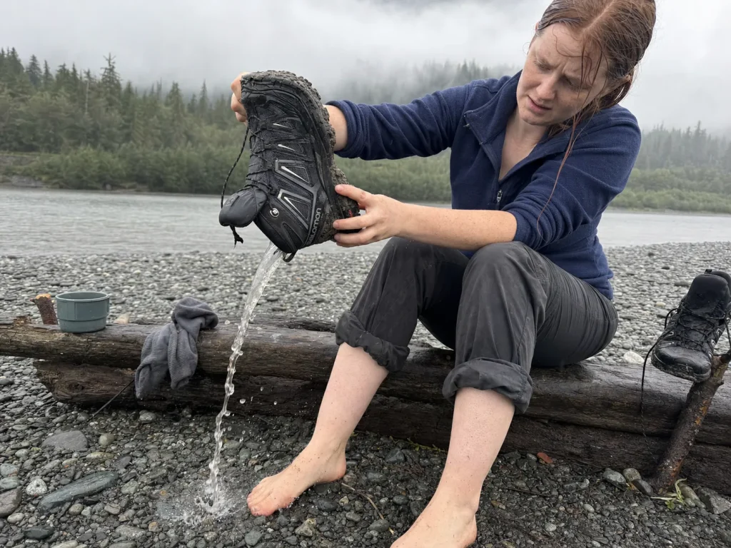 Hiker upending a waterproof Gore-Tex hiking shoe at camp to pour trapped water out