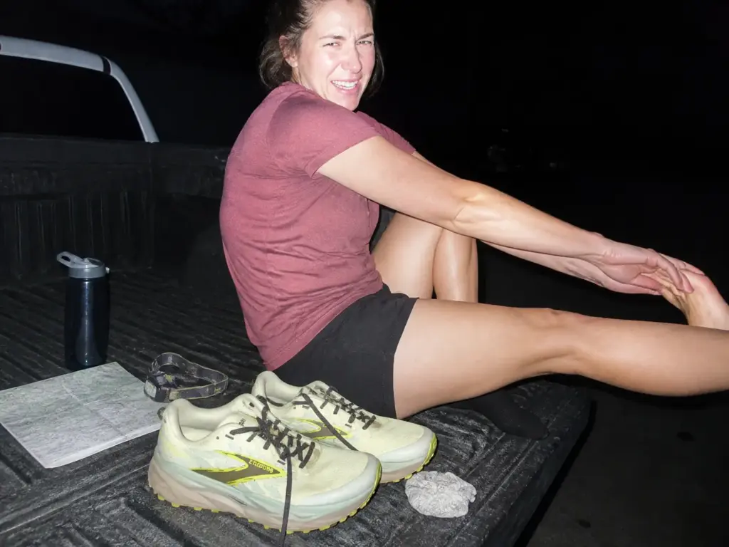 Hiker stretching a sore calf at the tailgate after a first hike in new trail runners