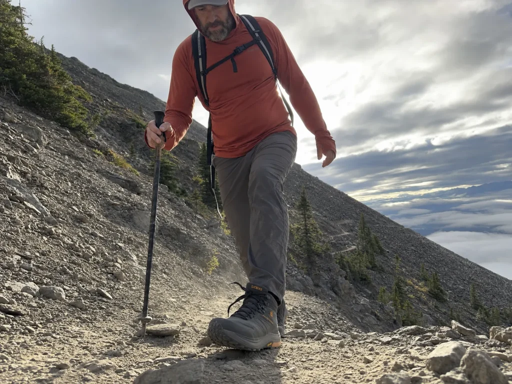 Low-drop hiking shoe mid-stride on a steep rocky descent showing foot strike and gait
