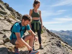 Choosing Stack Height: The Hiker’s Terrain-Specific Guide A full-body shot of a fit couple in their late 20s in hiking gear, pausing on a rocky trail to examine their shoes.