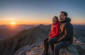 Down vs. Synthetic Insulation: A Performance Matrix for Hikers A man in a synthetic jacket and a woman in a down jacket stand on a mountain ridge at sunset, illustrating the choice between insulation types.