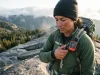 inReach vs SPOT Which Actually Sends Your SOS Hiker clipping a Garmin inReach Mini 2 to a pack strap on a ridge, inReach vs SPOT comparison