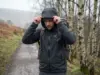 Gore-Tex vs eVent Which Membrane Breathes Better Hiker in a Gore-Tex hardshell pulling his hood up on a wet trail, rain gear membrane comparison