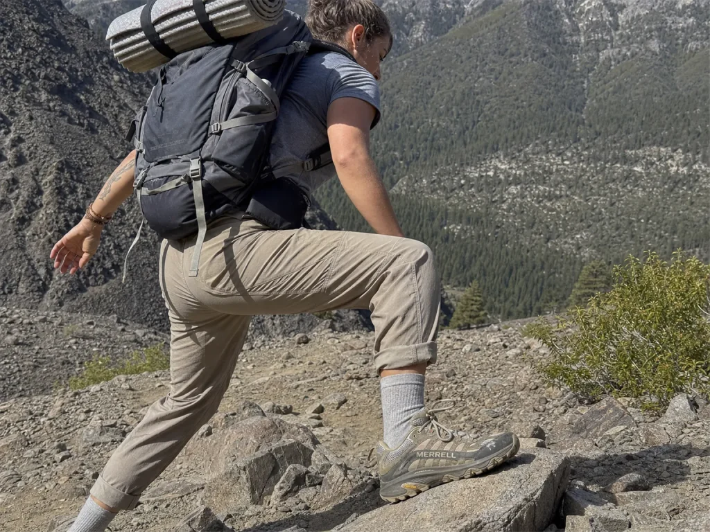 Hiker in Merrell Moab Speed shoes stepping across loose rock under a loaded backpack on a technical trail