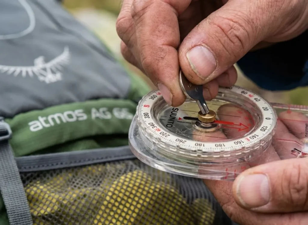 Macro shot of adjusting the declination screw on a Suunto MC-2 compass with a key.