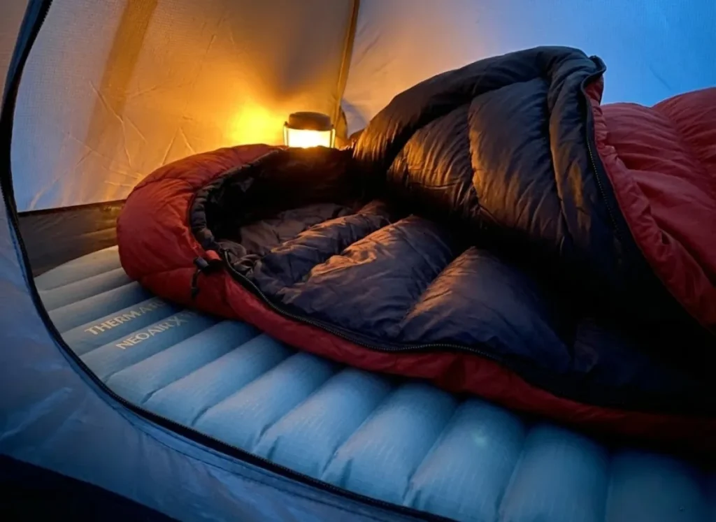 Macro photography of a high-end down sleeping bag and insulated sleeping pad, highlighting the texture and loft of the insulation.