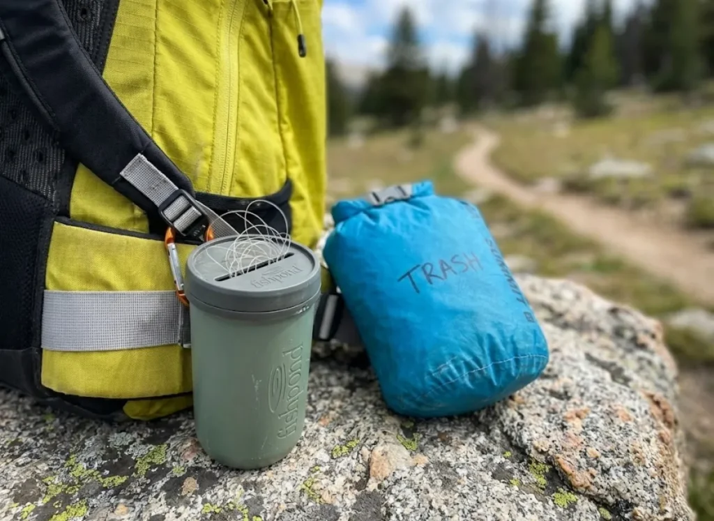 Fishpond PioPod attached to an Arc'teryx backpack hip belt next to a Sea to Summit trash dry sack.