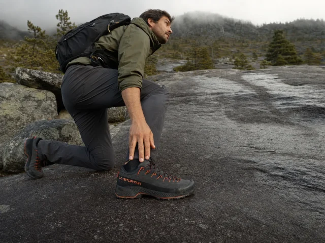 0-approach-shoes-vs-hiking-shoes-granite-slab Hiker in approach shoes stepping onto a wet granite slab where the dirt trail ends