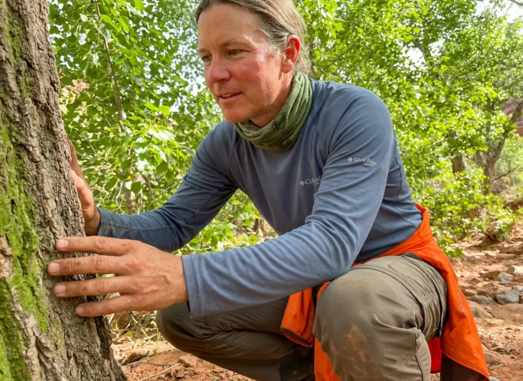 Hiker in Columbia gear identifying a Cottonwood tree in a dry desert wash.
