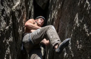 Four Way Stretch Fabric: Mobility vs. Durability A climber stemming a granite chimney, showing hiking pants stretching across the knee during a high step.
