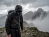 How to Wash Gore-Tex: The Ultimate Field-to-Laundry Guide A hiker walking through heavy rain on a mountain ridge, wearing a waterproof jacket that is saturated with water and no longer repelling rain.