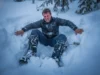 Post Holing Reality Check: Safety, Gear & Etiquette A exhausted winter hiker trapped thigh-deep in snow, struggling to climb out of a posthole in a dense forest.