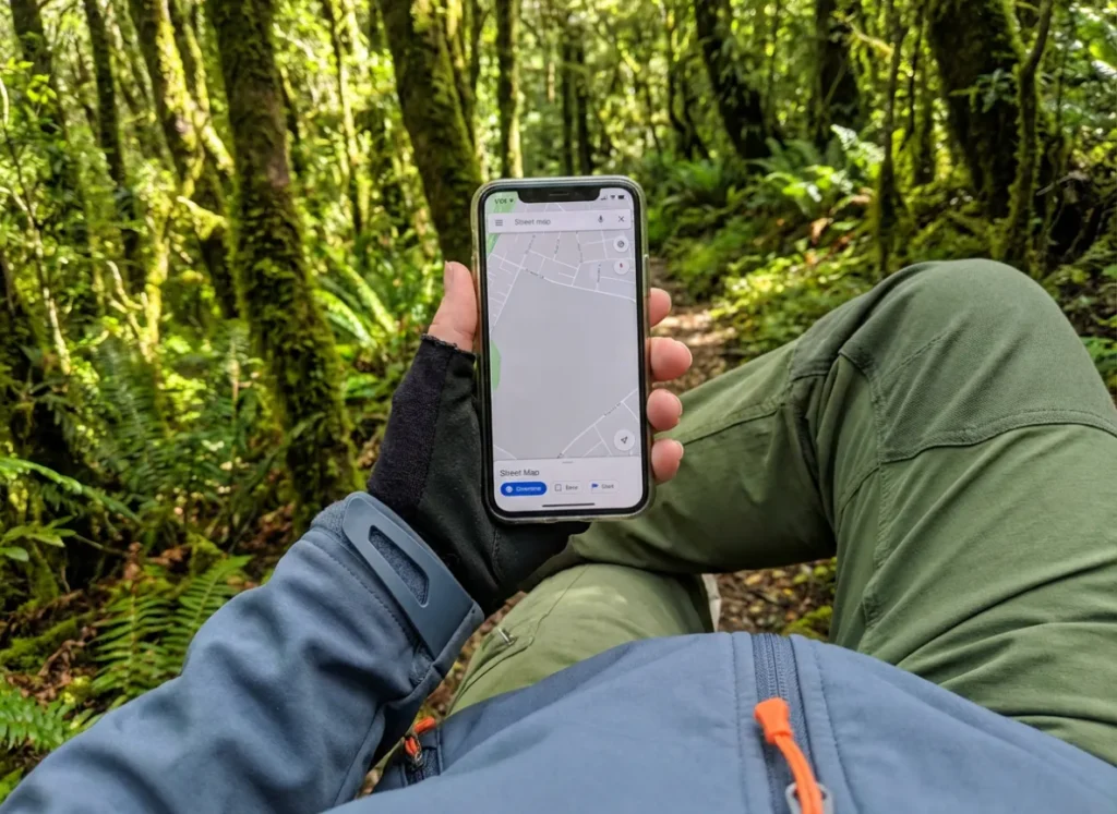 Point of view looking at a phone showing a blank map while standing on a clearly visible forest trail.