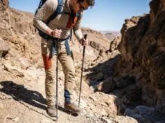 Snake Bite While Hiking: The Walk Out vs. Wait Protocol A hiker freezing mid-step on a rocky desert trail, scanning the ground for snakes.