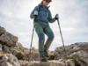 Using Trekking Poles Downhill: The Knee-Saving Guide A hiker descending a steep rocky trail using trekking poles to support her weight.