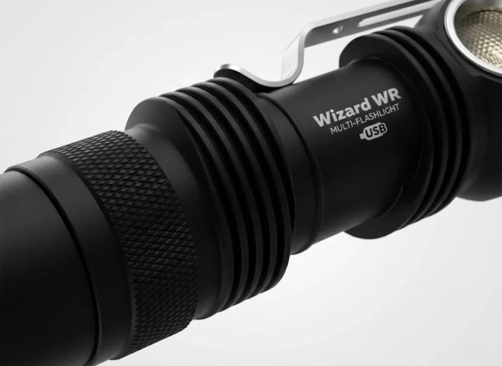 Macro studio shot of a rugged, military-grade aluminum headlamp body showing cooling fins and precise knurling textures.