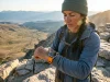 8 GPS Hiking Watches Compared Only 2 Call for Help Hiker checking a Garmin Fenix 8 GPS hiking watch on a ridgeline at golden hour