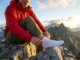 The Hiking Fabric Friction Index: Understanding Skin Liner Coefficients A professional hiker on a granite ridge adjusting a white technical liner sock, with golden hour lighting highlighting the texture of the fabric and high-end outdoor apparel.