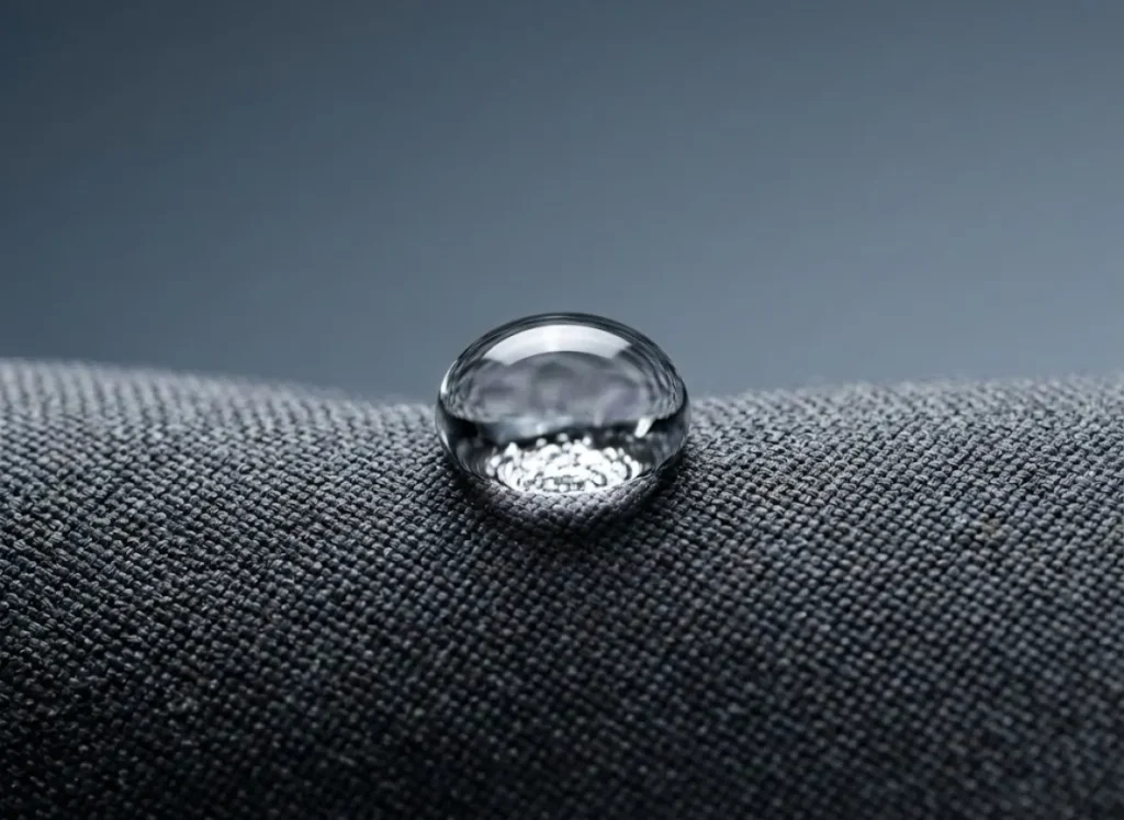 Extreme macro photography of a water droplet beading on Gore-Tex Pro fabric, demonstrating hydrostatic resistance and surface tension.