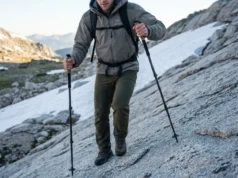 Rewire Trail Balance: Proprioception & Trekking Poles Low angle shot of a hiker descending granite, planting a carbon fiber trekking pole with precision, wearing premium Arc'teryx gear under alpine sunlight.