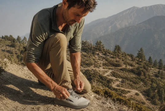 Hiking Shoe Toe Bumper Protection What to Feel For Hiker re-tensioning laces on Altra Lone Peak 9 shoes at the top of a steep descent