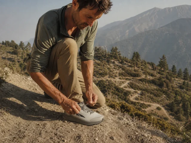 0-hiking-shoe-toe-bumper-lacing-before-descent Hiker re-tensioning laces on Altra Lone Peak 9 shoes at the top of a steep descent