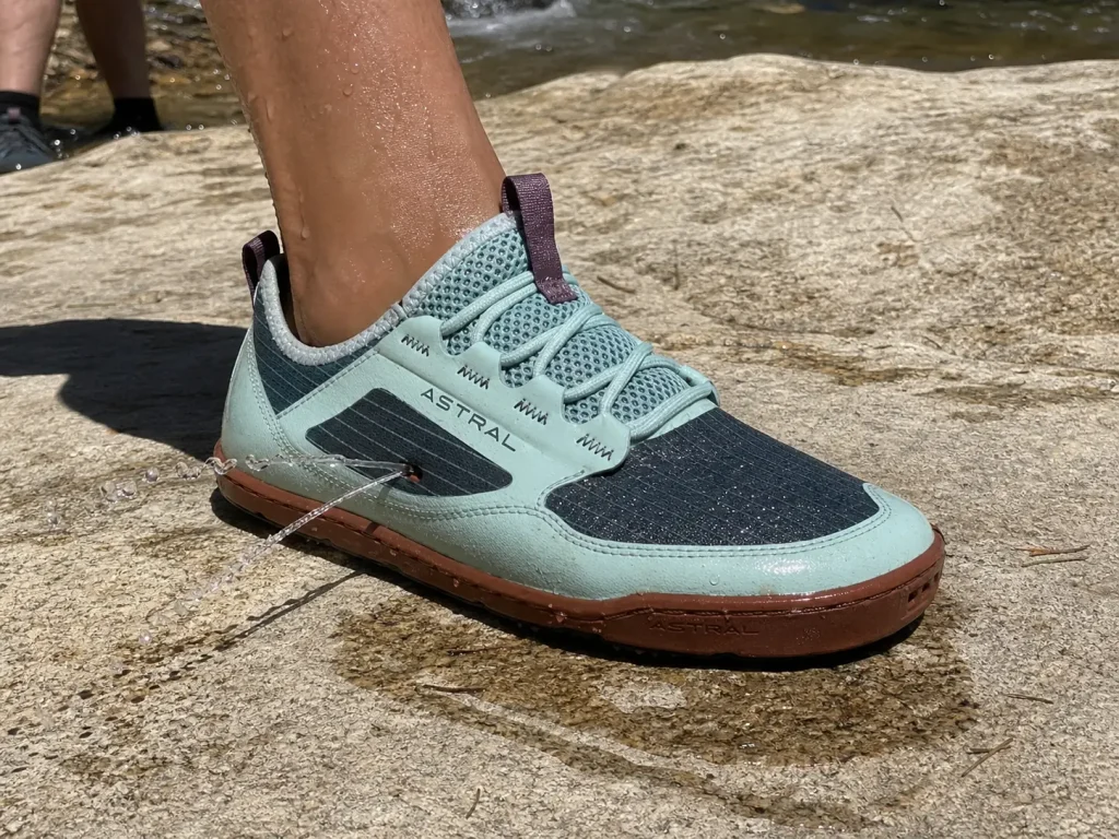 Close-up of water jetting out of the drainage ports of a hiking shoe on the first step out of a creek