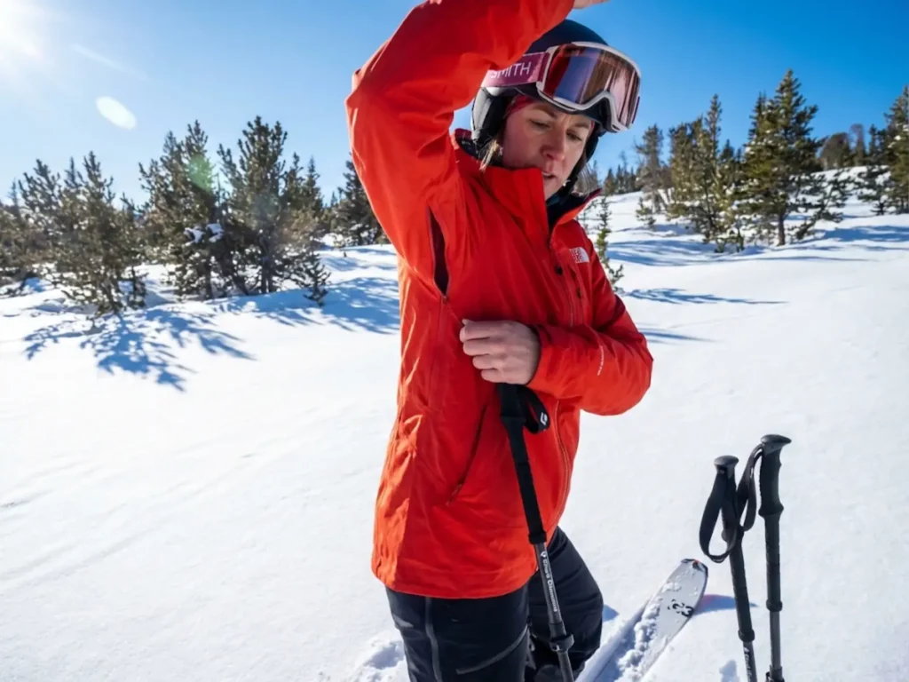 Ski tourer venting pit zips on breathable shell jacket during uphill climbing